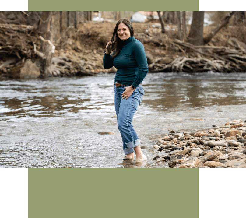 A woman standing in the water near some rocks.