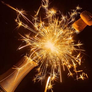 A bottle of champagne with a sparkler in the middle.