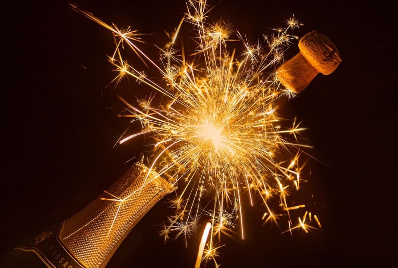 A bottle of champagne with a sparkler in the middle.