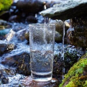 A glass of water is sitting on the rocks
