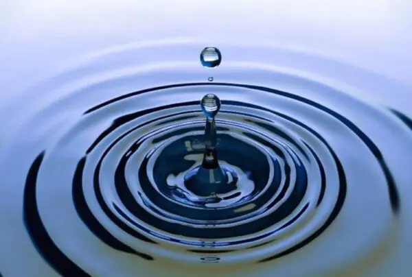 A water drop falling into the ocean with a wave coming out of it.