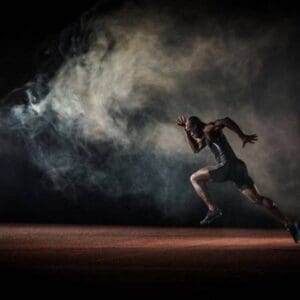 A man running in the dark with smoke coming from behind him.