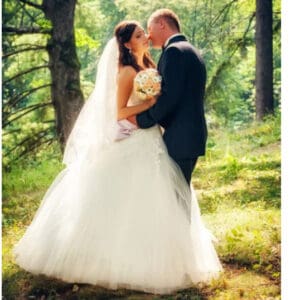 A bride and groom kissing in the woods