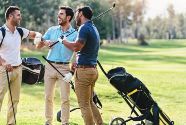 Two men are playing golf and one is holding a bag.